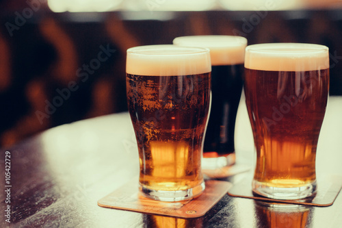 Obraz na płótnie Glasses of light and dark beer on a pub background.