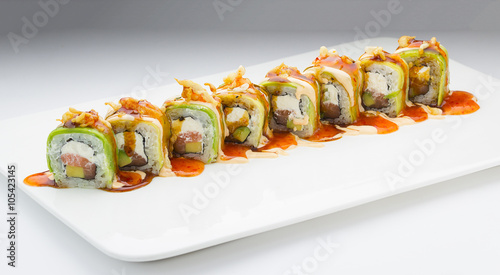 Sushi with avocado salmon and cheese. Crunch Roll. With delicious sauces. On a plate over white background.