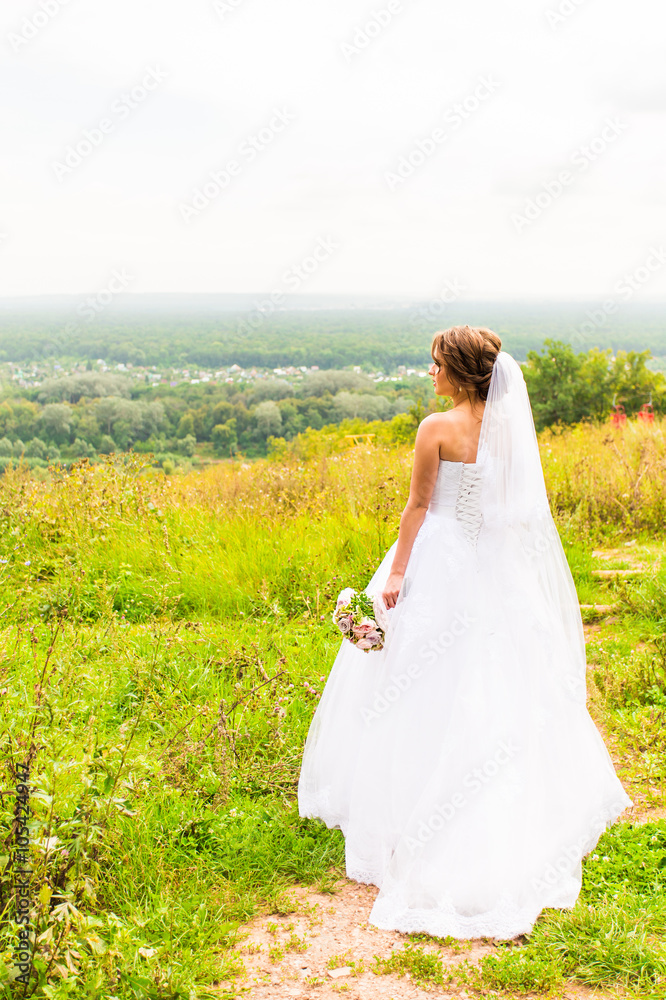 Beautiful bride girl in wedding dress  and bouquet of flowers, outdoors portrait