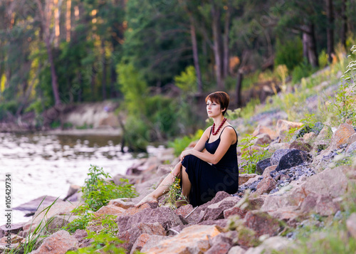 beautiful girl with flowers on the stoned river bank on forest b