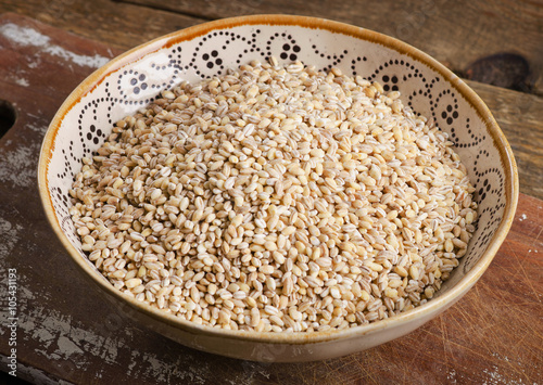 Barley in a ceramic bowl on a wooden board.