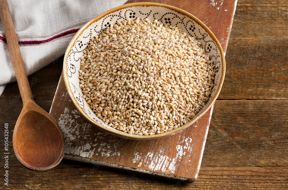 Barley in a bowl on a rustic wooden board. Barley in a bowl on a rustic wooden board.