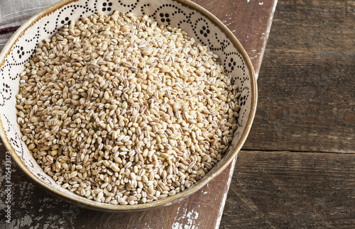 Barley in a bowl on a rustic wooden board.