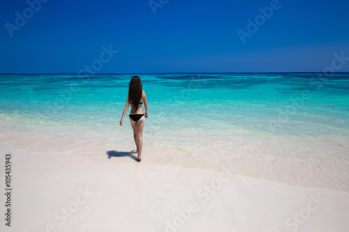 Fototapeta Enjoyment. Beautiful bikini woman walking on tropical beach, sli