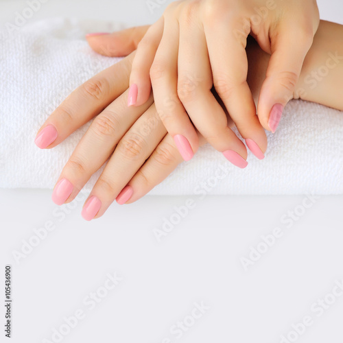 Hands of a woman with pink manicure are on a towel