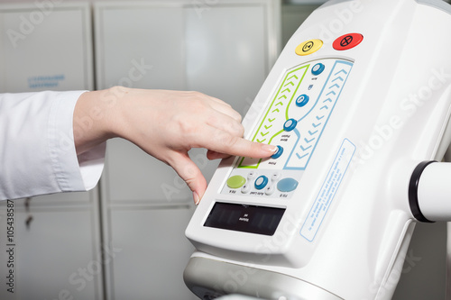 A female doctor's hand on contrast injector for CT scanner. Computerised tomography