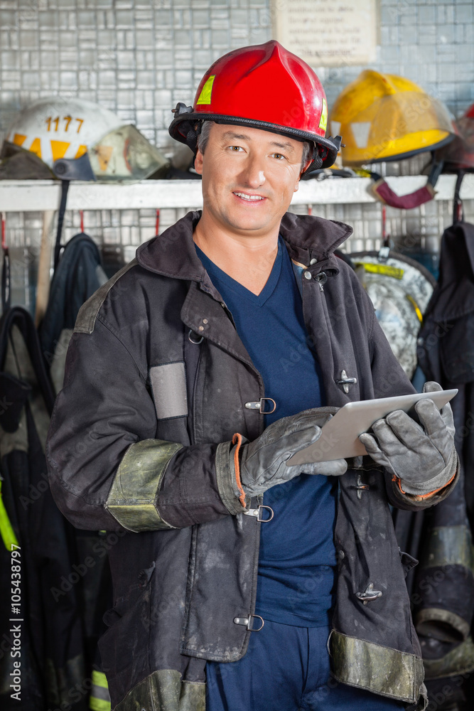 Obraz premium Smiling Fireman Holding Digital Tablet At Fire Station