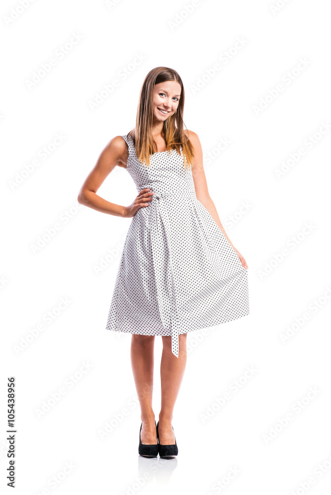 Girl in black-and-white dotted dress, heels, studio shot
