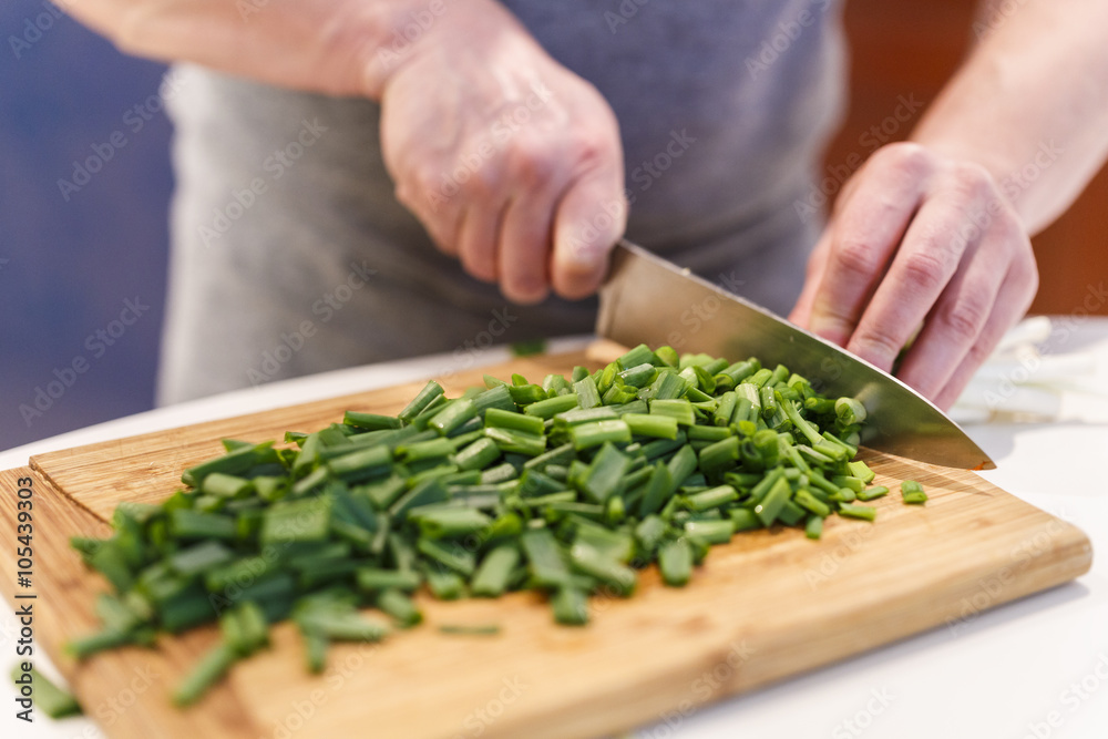man chopped green onion on the board. Wooden table man chopped green onion on the board. Wooden table