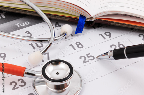 Foto Close up of stethoscope and pen on calendar, doctor appointment.