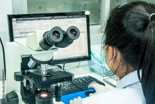 women  use microscope for find microscopic organism on the table
