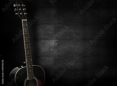 Black acoustic guitar on dark black wooden background. © SlayStorm