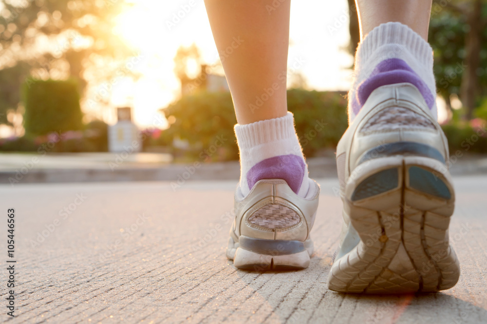 Runner feet running on road closeup on shoe. woman fitness sunri