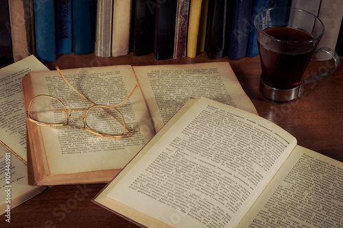 Открытые книги на столе, очки и кружка