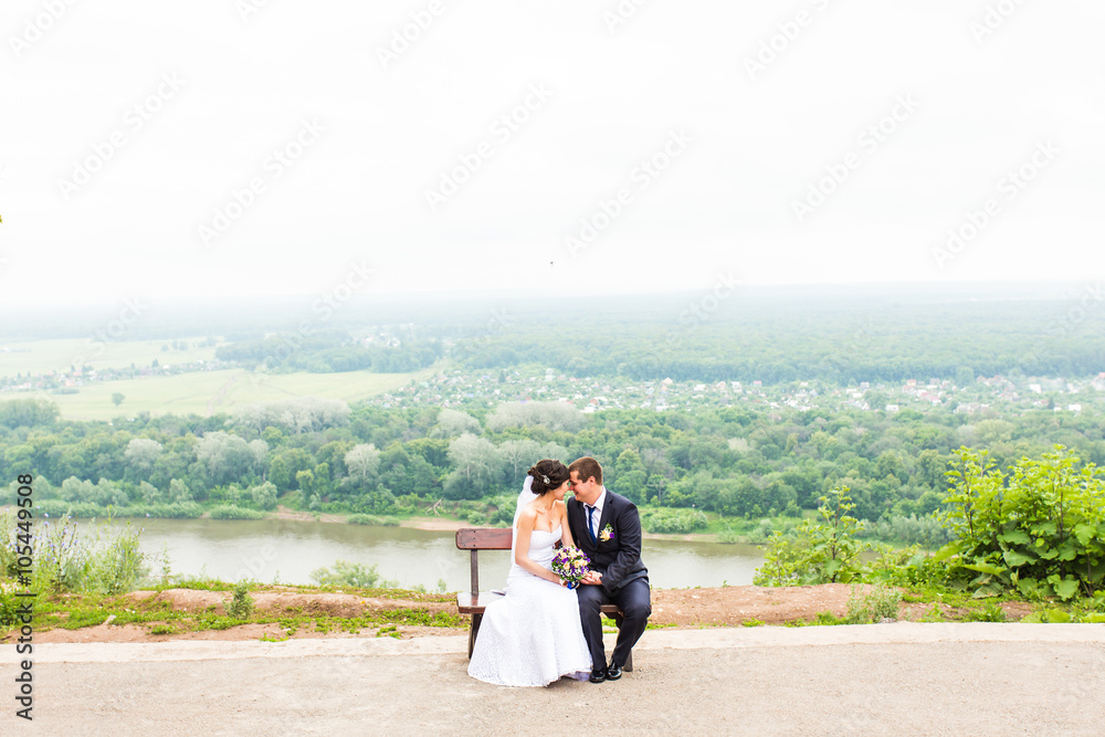 attractive bride and groom sitting on a bench attractive bride and groom sitting on a bench
