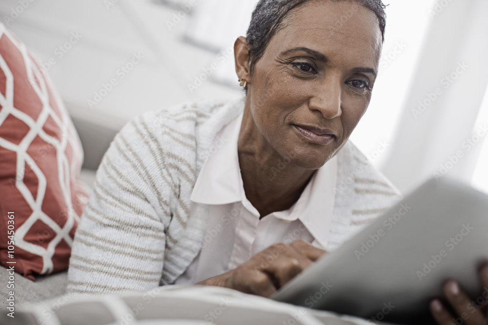A mature woman lying on the sofa, using a digital tablet, A mature woman lying on the sofa, using a digital tablet,
