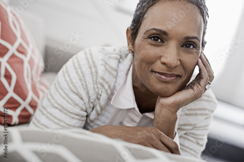A woman at home lying on the sofa, resting her chin on her hands, 