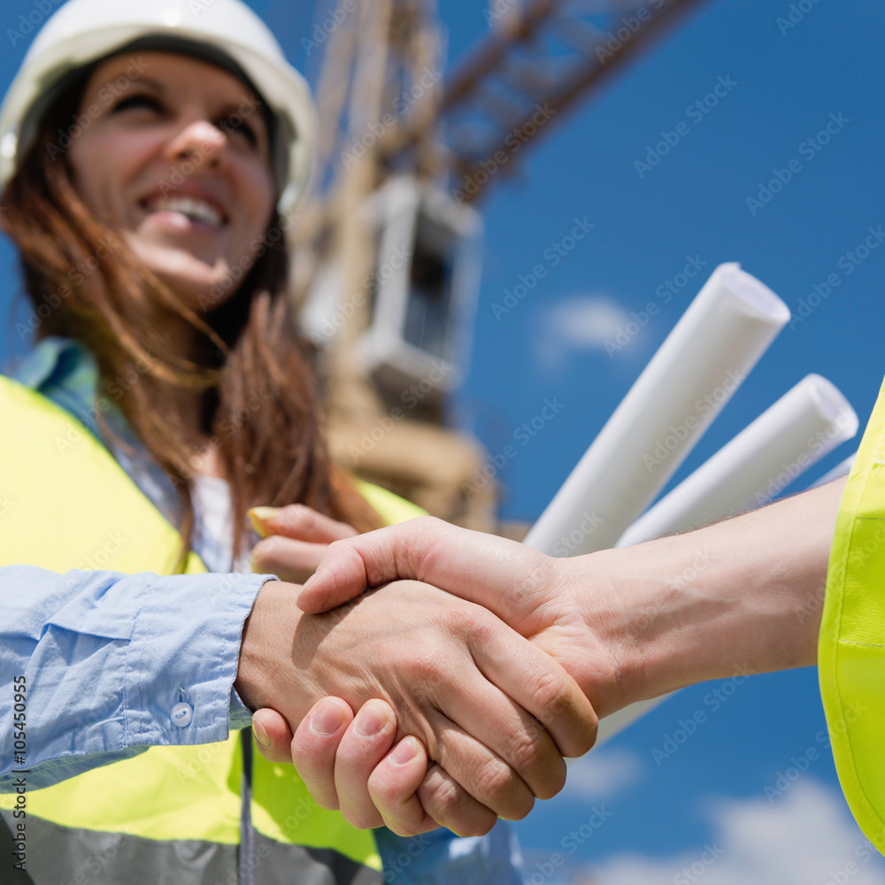 Architect at construction site, shaking hands with engineer