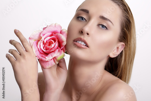 Beauty blonde young woman showing a fresh flower on white