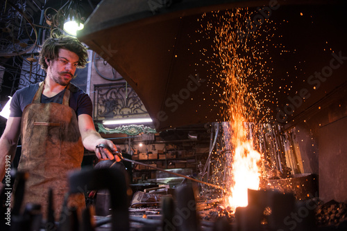 Photos Ironworker forging hot iron in workshop