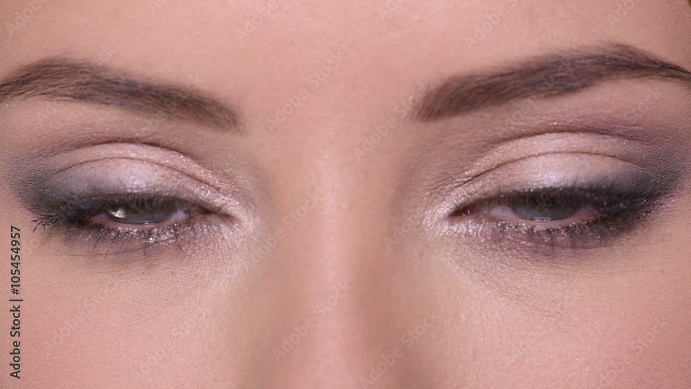 Closeup of opens women's eyes with color eye makeup.