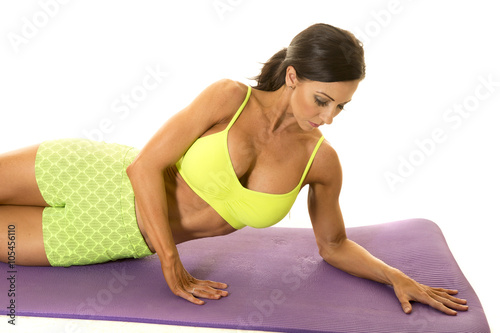 woman in green sports bra and shorts lay side look down