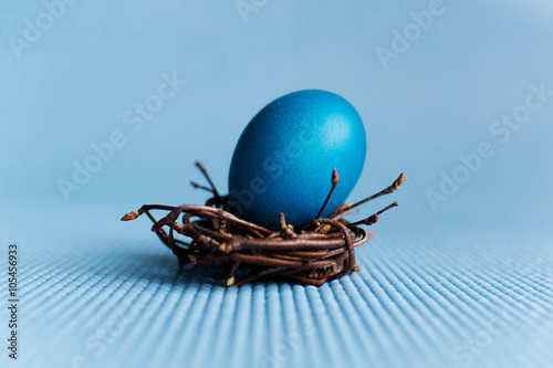Blue Easter egg in the nest on blue background photo
