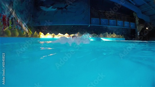 Teen boy swimming underwater in pool.