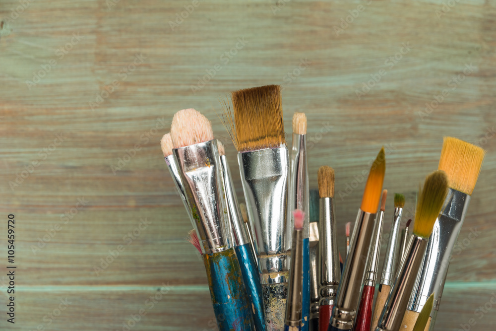 Fototapeta premium Artist paint brushes over rustic wooden texture.