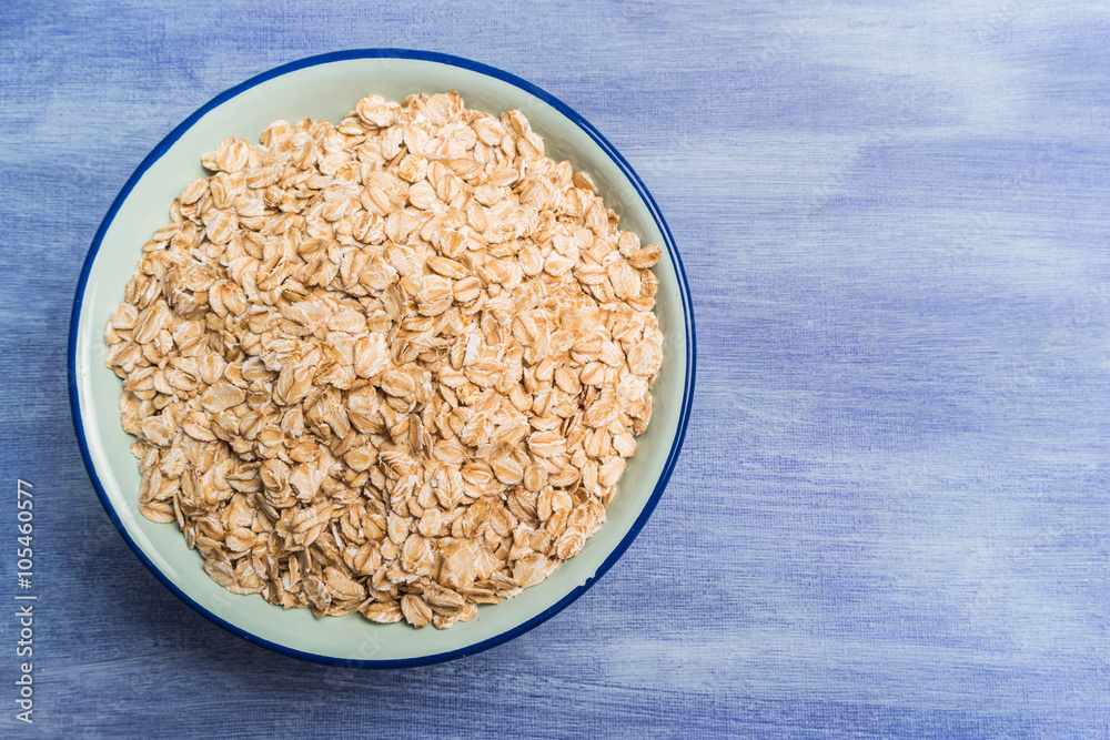 Oat flakes in a bowl on rustic textured background Oat flakes in a bowl on rustic textured background