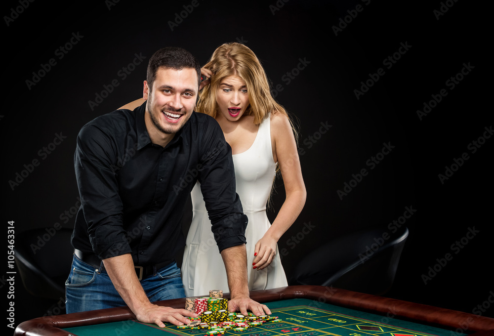Young couple celebrating win at roulette table in casino. Young couple celebrating win at roulette table in casino.