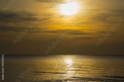 Sun sets over horizon of ocean. Sky  water and shore.