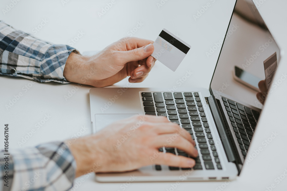 Man hands holding credit card on laptop Man hands holding credit card on laptop