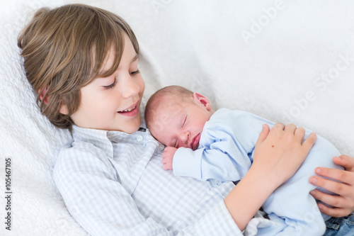 Konstfotografi Happy laughing boy holding his sleeping newborn baby brother