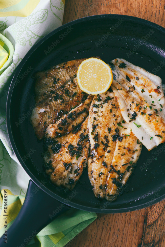 Flounder fillet roasted in a skillet with herbs and lemon butter Stock
