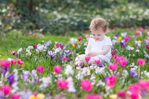Bautiful funny baby girl playing in a field of flowers
