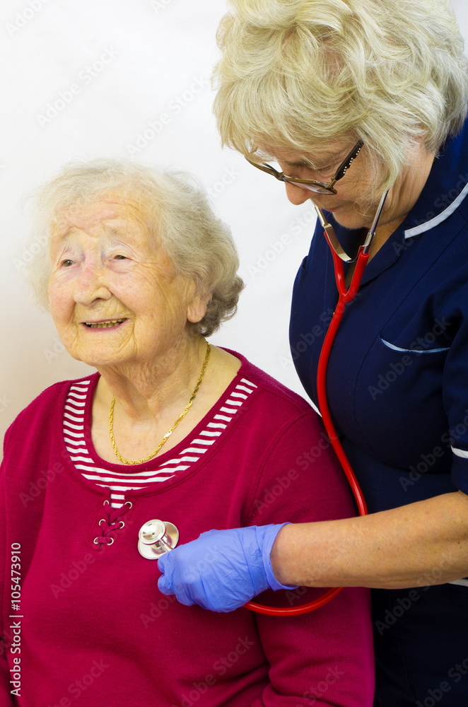 A senior lady having a medical check with a nurse listening with a stethoscope. A senior lady having a medical check with a nurse listening with a stethoscope.