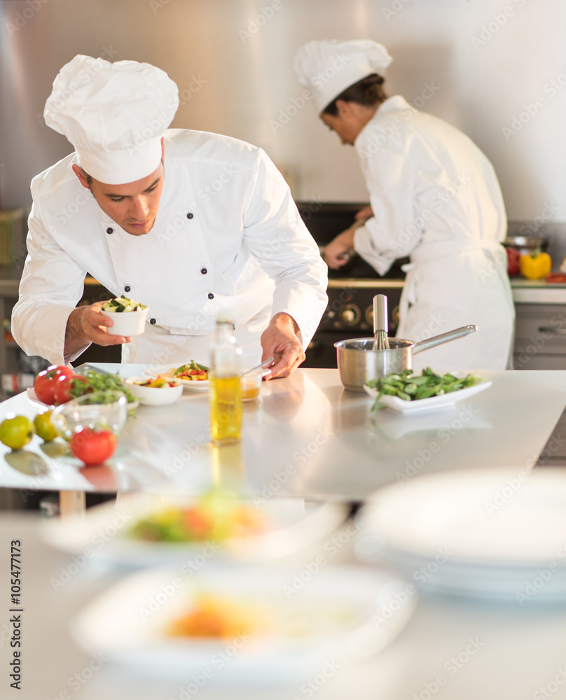 Two chefs are working in a starred restaurant kitchen.