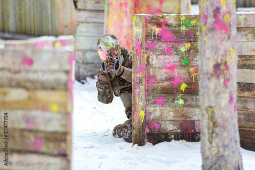 Paintball game in winter. Cool shooter behind fortification.