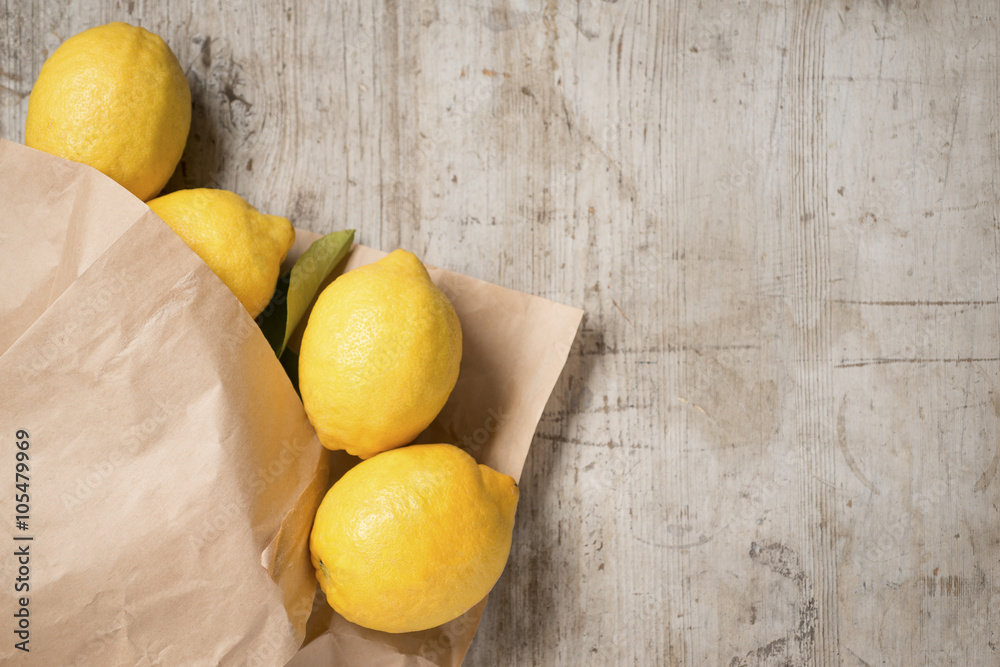 Lemons in a brown paper bag against a wooden background