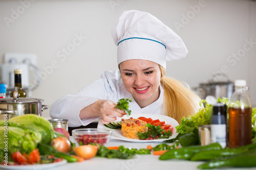 Happy cook preparing vegetable salad with cheese