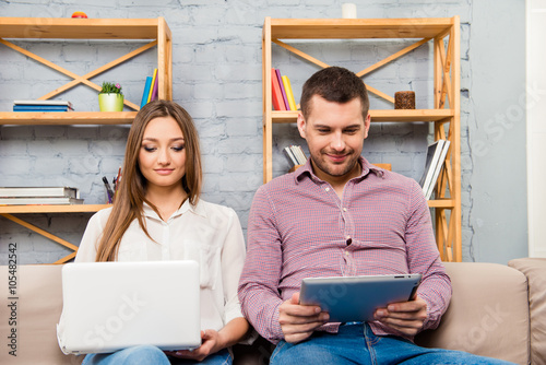 Excited man and woman sitting on couch with laptop and tablet photo