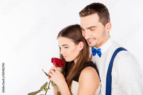 Portrait of smiling man and attractive woman holding red rose