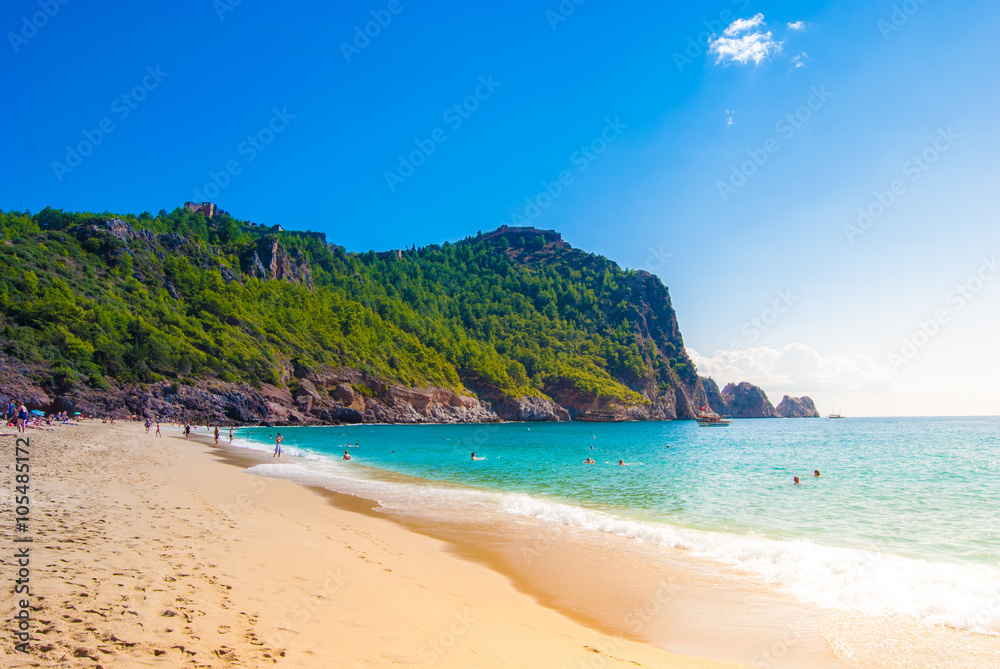 Beach of Cleopatra with sea and rocks of Alanya peninsula, Antalya, Turkey. Beautiful landscape of tourist destination with high green cliff and Castle of Alanya.