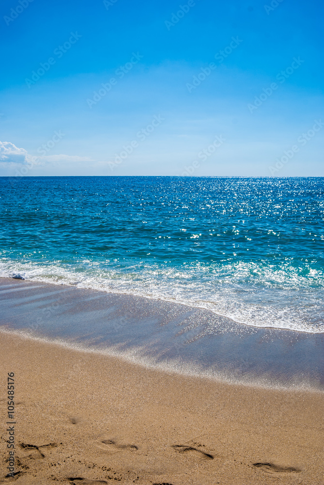 Yellow sandy beach and blue sea with waves and seafoam. Background image for travel, summer vacation, and recreation. Vivid photo of tropical paradise. Yellow sandy beach and blue sea with waves and seafoam. Background image for travel, summer vacation, and recreation. Vivid photo of tropical paradise.