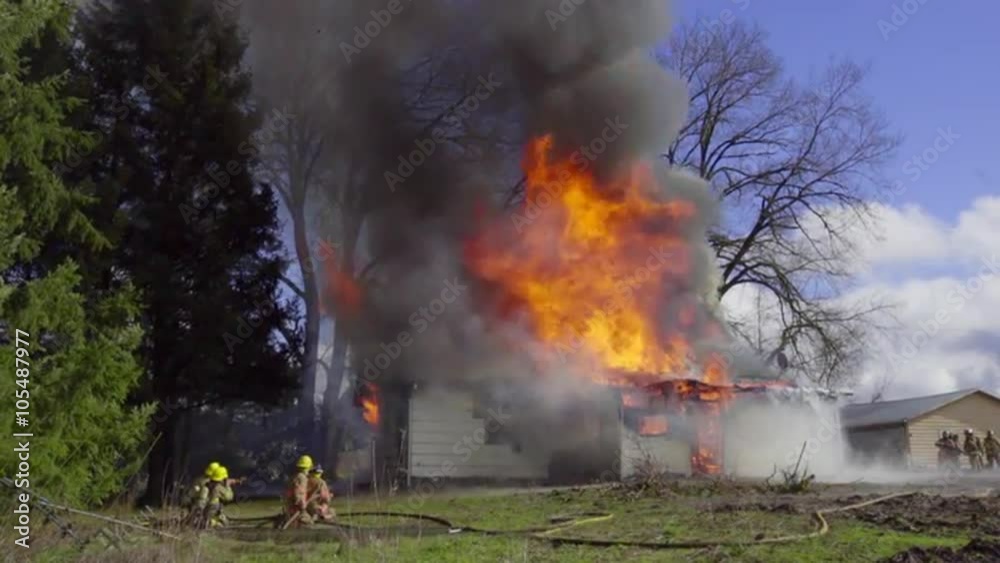 Wide shot of firefighters preparing to deal with huge fire within burning home Wide shot of firefighters preparing to deal with huge fire within burning home