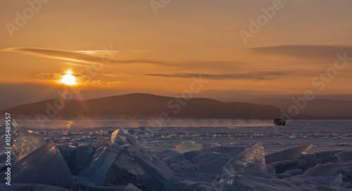Car goes on ice on background sunrise. © Julia Mashkova