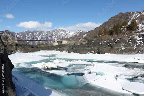 Opening of ice on the turquoise Katun River in the spring near Oroktoysky Bridge, Altai, Russia 