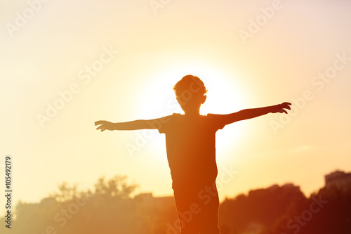 silhouette of happy little boy at sunset