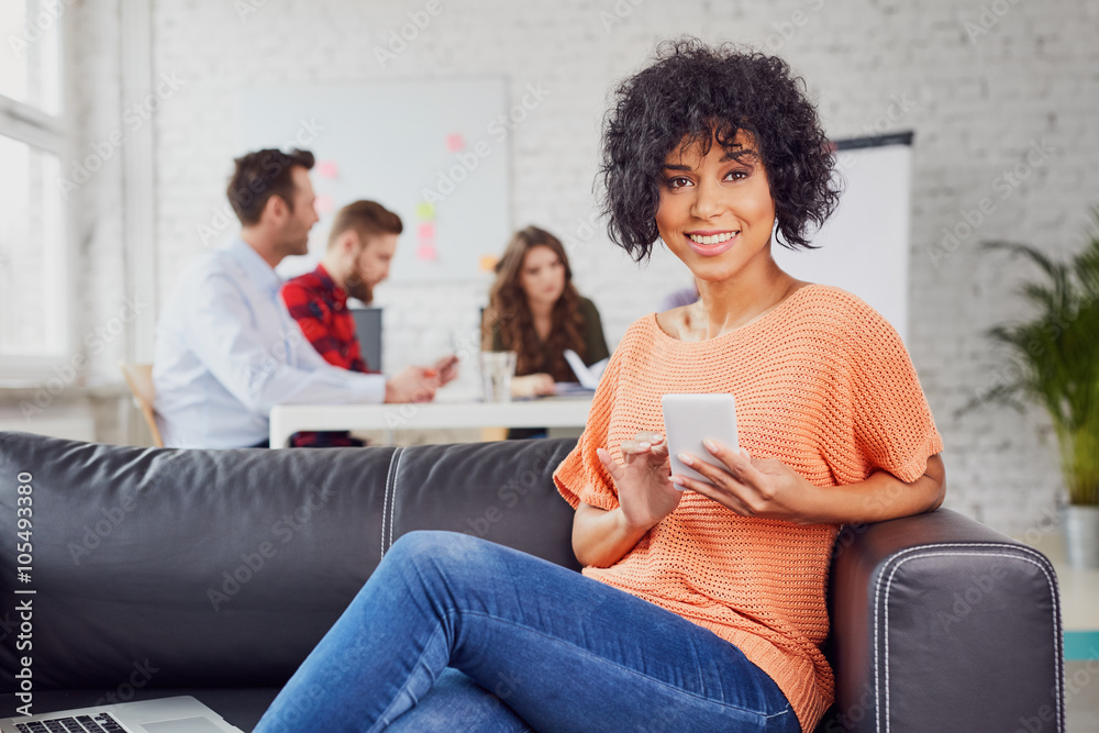 Happy young woman with smartphone on couch in modern office Happy young woman with smartphone on couch in modern office